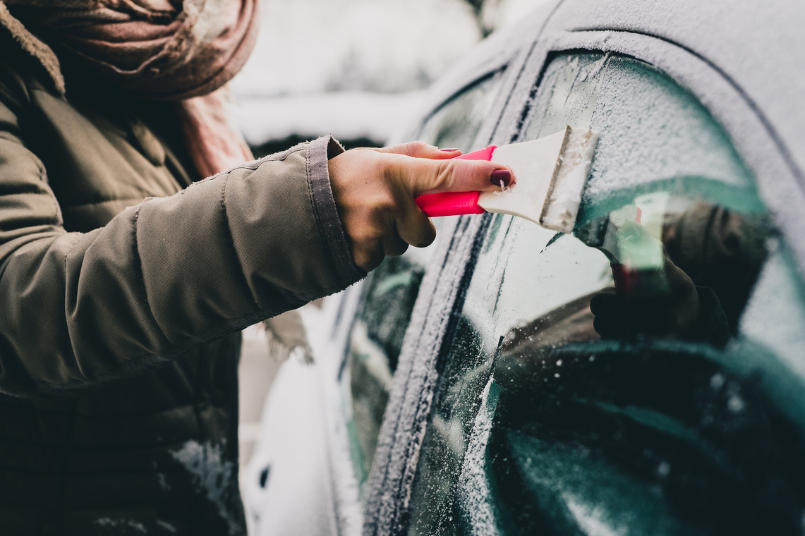 Woman scraping icy window of a car