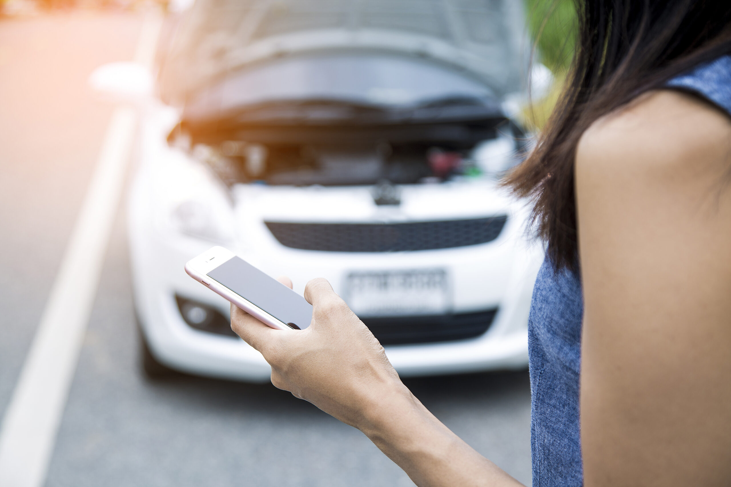 Car engine broken down and person holding phone vehicle